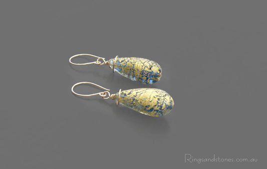 Gold earrings with large Murano glass beads in gold and light blue.