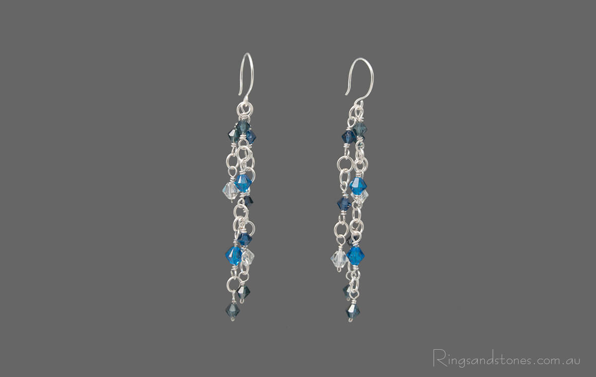 Pair of sterling silver wire wrapped long earrings with Blue Swarovski crystals.